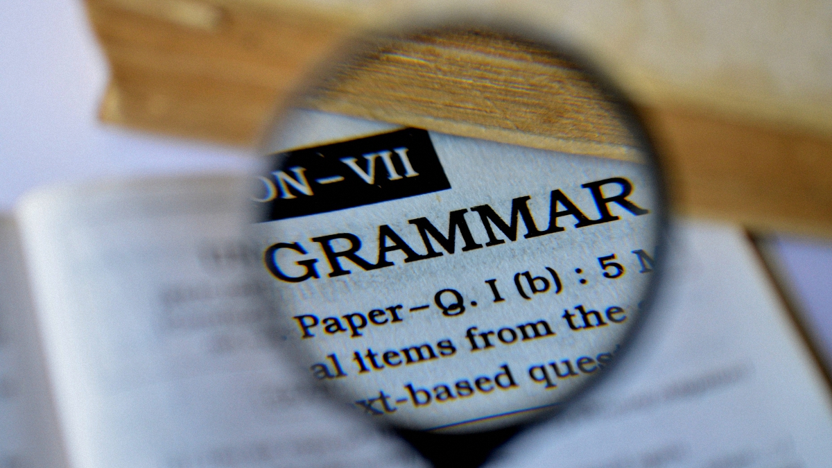 a magnifying glass hovering on the grammar word in a dictionary