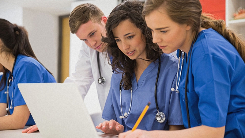 Medical students having a discussion while looking at a computer